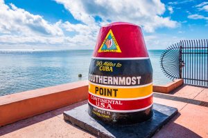 Charter flights to the Bahamas and in Florida Large, colorful buoy marking the Southernmost Point in the continental USA, with the ocean and sky as a backdrop, located in Key West. Visitors can easily access this landmark via Key West Charter Flights for a seamless journey to paradise. Charter a plane to the Bahamas or in Florida