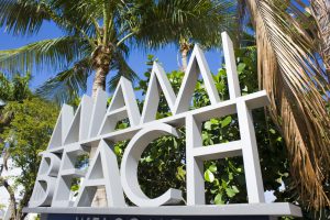 Miami beach welcome sign with palm trees.