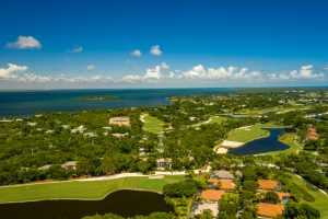 An aerial view of a golf course and the ocean, ideal for those looking to charter flights in the Bahamas or Florida.