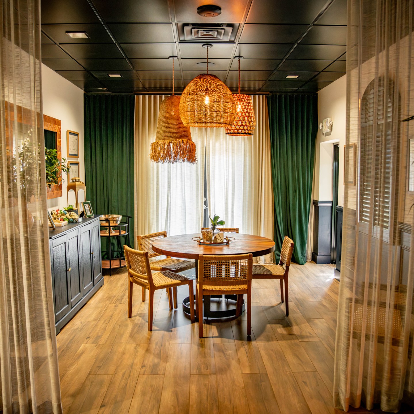 Cozy dining room with round table, chairs, plants, and warm lighting.
