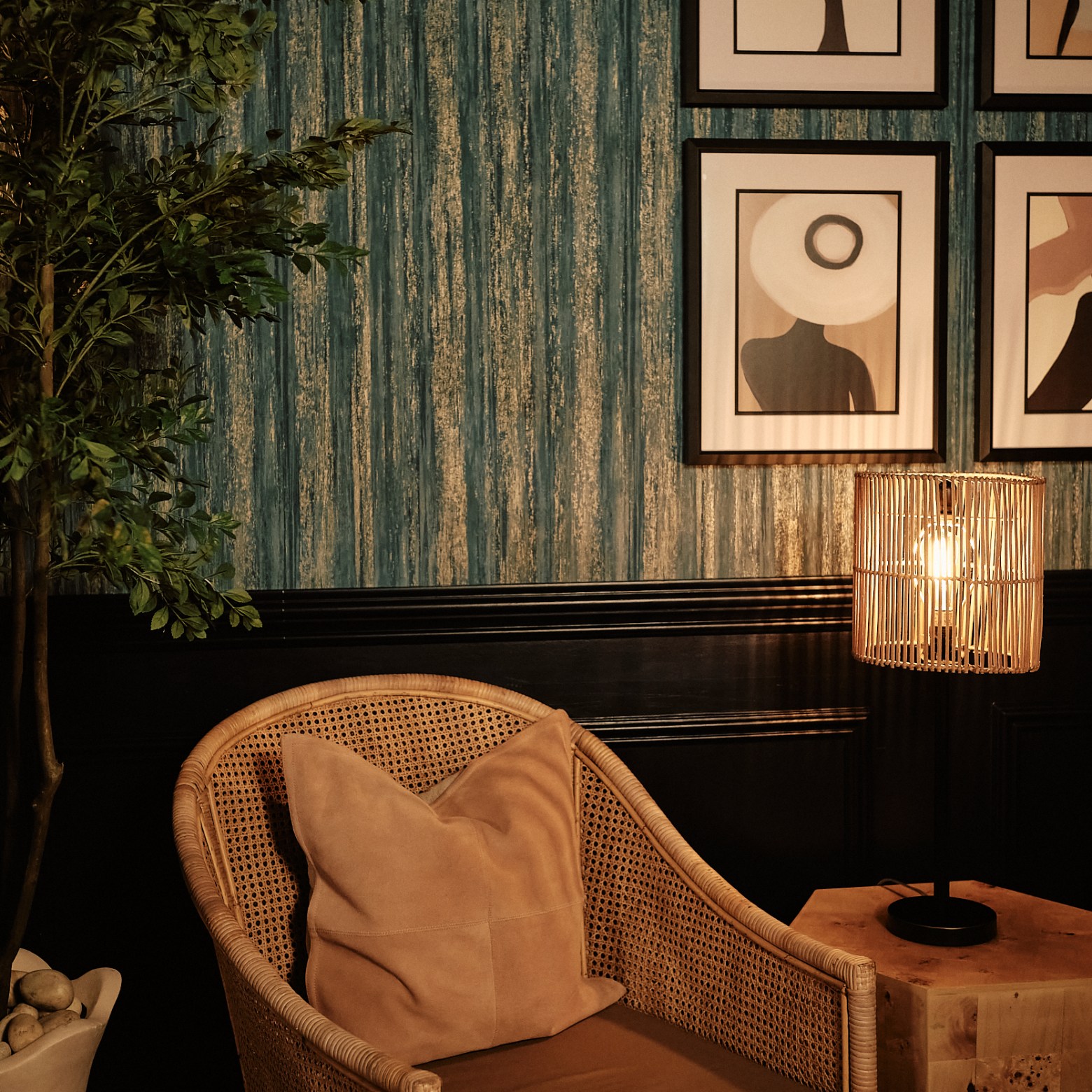Cozy chair, wood lamp on table, framed art on textured blue wall.