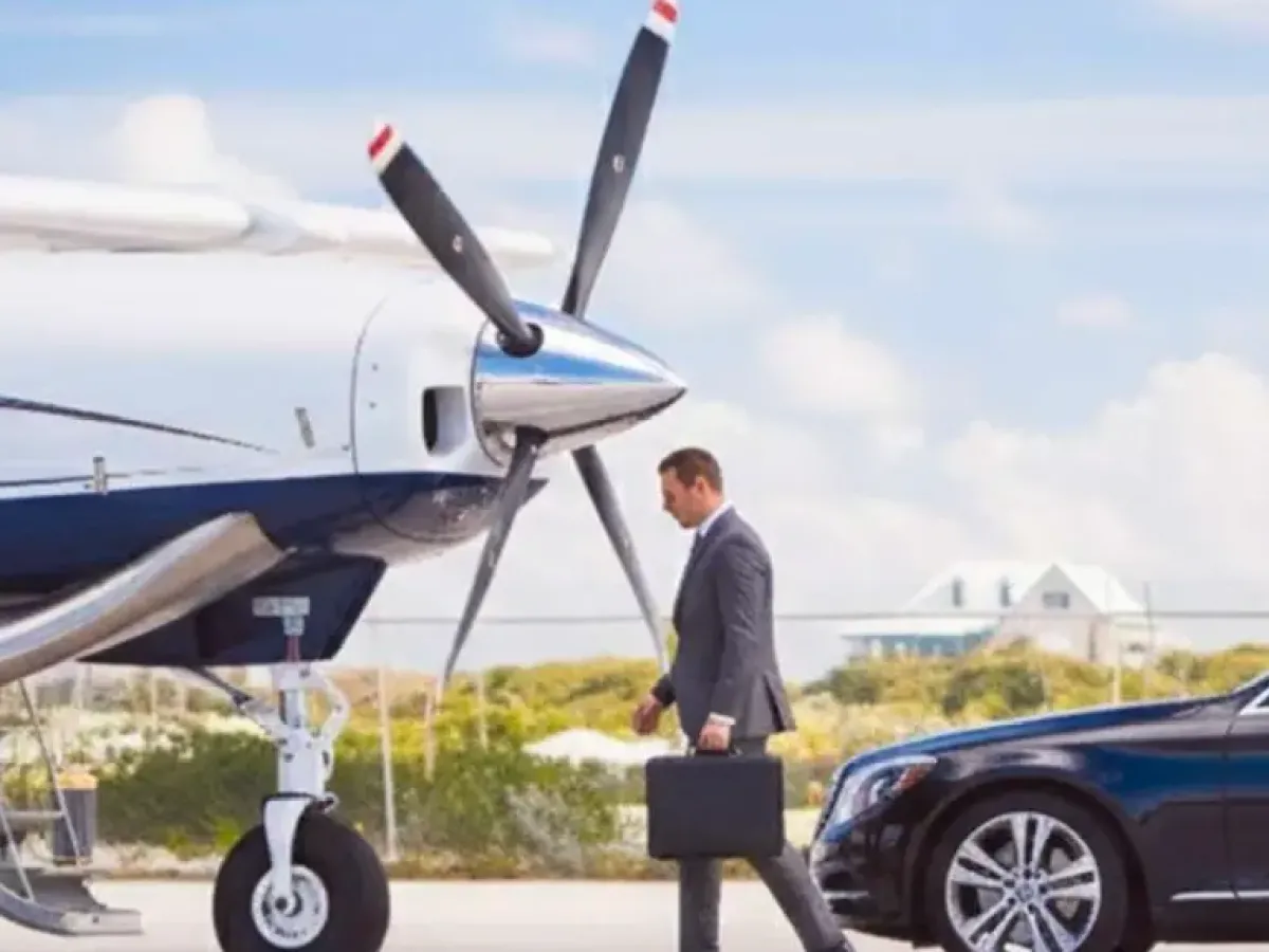 Man in suit with briefcase walks toward private plane, car nearby, blue sky background.